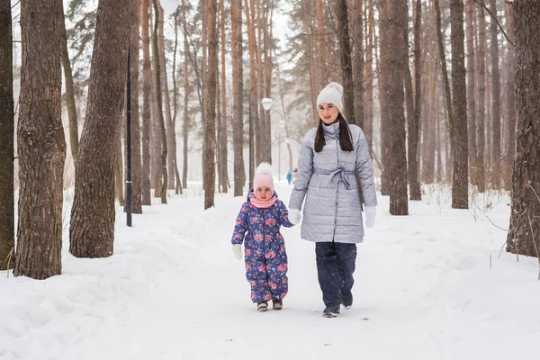 Family, motherhood and nature concept - Mother with her child walking in the winter park — Stock Photo, Image