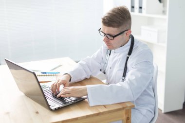 Tıp, çalışma ve insan kavramı - Doktor masada oturan ve dizüstü bilgisayarda çalışma