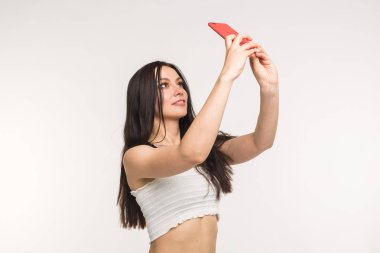 Teknoloji ve insan kavramı - selfie fotoğraf yapma ve beyaz arka plan üzerinde gülümseyen genç kadın