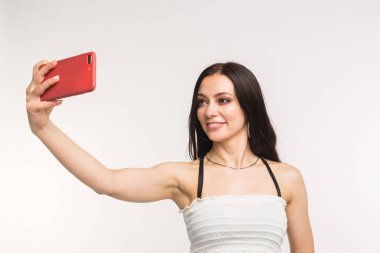 Teknoloji ve insan kavramı - selfie fotoğraf yapma ve beyaz arka plan üzerinde gülümseyen genç kadın