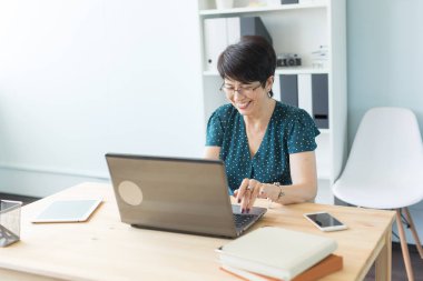 İş insan ve teknoloji kavramı - orta yaş kadın ofiste dizüstü bilgisayar ile çalışma