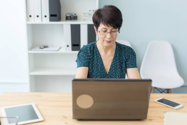 İş, insan ve teknoloji kavramı - orta yaşlı bir kadın ile dizüstü bilgisayar çalışma vasıl ev ya da ofis