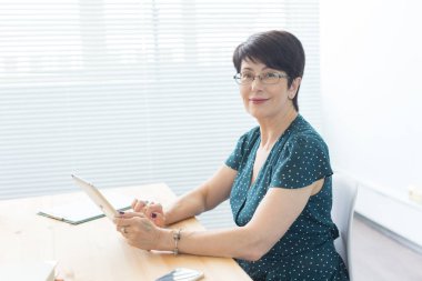 İnsanlar ve teknolojileri kavramı - orta yaşlı bir tablet kullanma office iş kadını