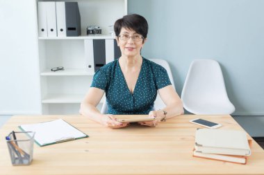 İş ve insan kavramı - orta kendine güvenen kadın ofiste tablet ile çalışma yaşında