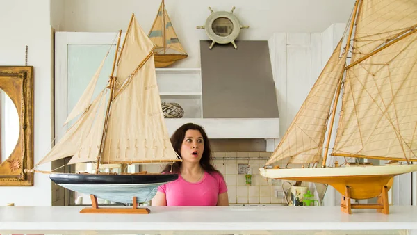 Hobbi, az érzelmek és a gyűjtő fogalom - fiatal meglepett nő keres elrendezés a konyhában a vitorláshajó — Stock Fotó
