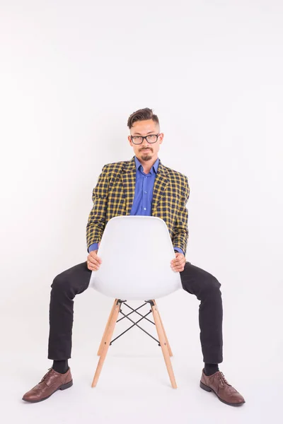 Concepto de moda y gente - hombre guapo barbudo seguro sentado en la silla sobre fondo blanco — Foto de Stock