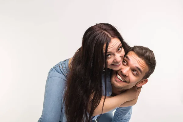 Divertimento e conceito de relacionamento - Homem carregando namorada de costas no fundo branco — Fotografia de Stock