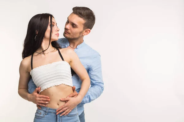 Junger Mann umarmt seine Freundin auf weißem Hintergrund mit Kopierplatz — Stockfoto