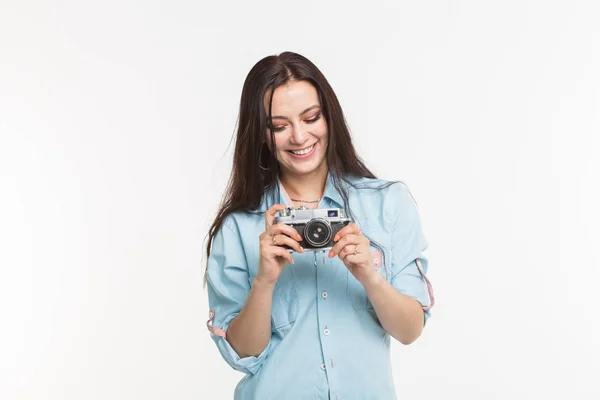 Happy european female model with dark hair enjoying indoor photoshoot. Young woman is looking at her vintage camera on white background — Stock Photo, Image