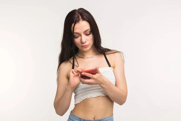 Technológia és az emberek koncepció - fiatal nő valamit neki a telefon vigyáznak a fehér háttér — Stock Fotó