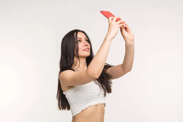 Technológia és az emberek koncepció - fiatal nő, így egy selfie fotó, és mosolygott, fehér háttér — Stock Fotó