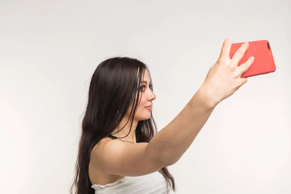 Technologie en mensen concept - jonge vrouw maken een selfie foto en glimlachend op witte achtergrond — Stockfoto