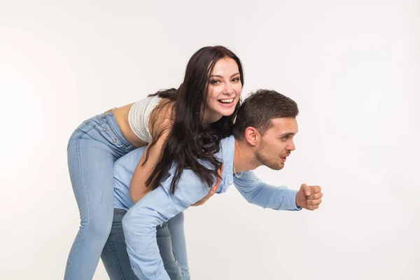 Paar posiert auf weißem Hintergrund - Mann hält Frau auf dem Rücken — Stockfoto