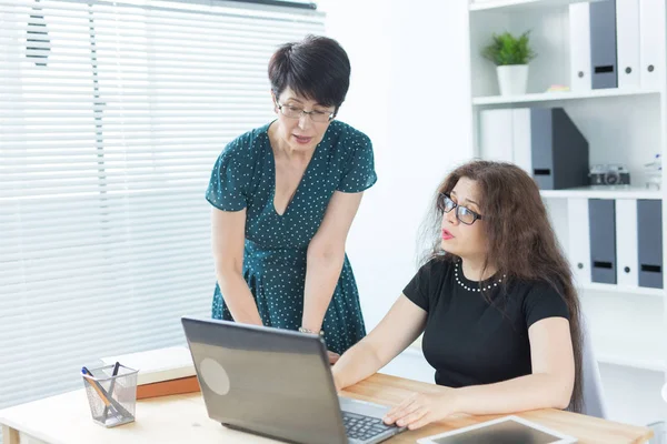 Geschäftsleute, Technik und Kommunikationskonzept - Dame mittleren Alters hilft ihrer Kollegin mit Laptop — Stockfoto