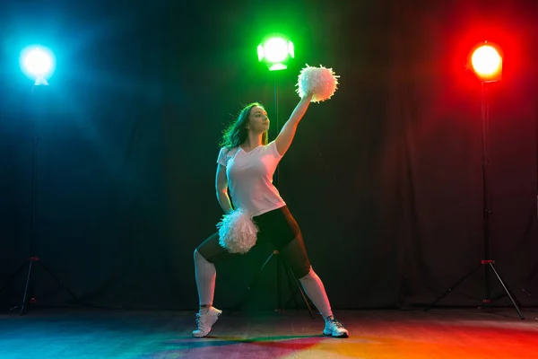 Animadora joven bailando con pompones sobre fondo colorido — Foto de Stock