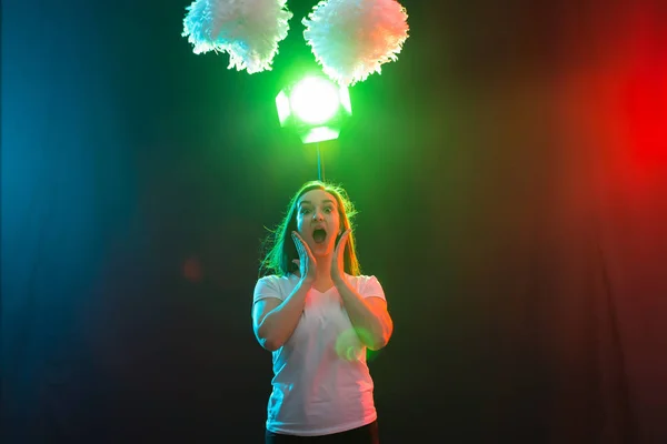 Concepto de danza, deporte y gente: una hermosa joven bailando en la oscuridad con pompones y sonriendo — Foto de Stock