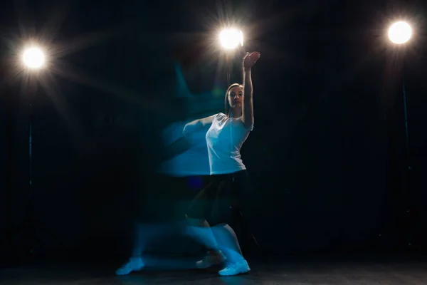 Concetto di danza, sport, bellezza e persone - la giovane donna che danza nell'oscurità è balzata in una luce colorata — Foto Stock