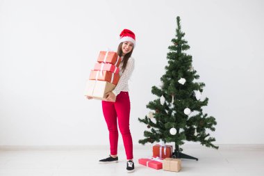 Noel ve tatil kavramı - santa şapka hediye kutuları yığını beyaz arka plan üzerinde tutan genç kadın