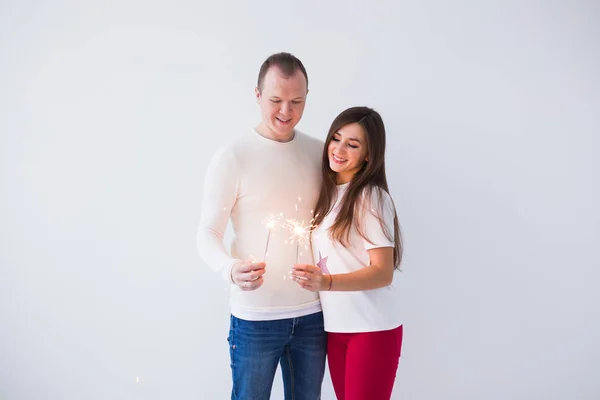 Conceito do Dia dos Namorados - Jovem feliz sorrindo alegre casal atraente celebrando com sparklers no fundo branco — Fotografia de Stock