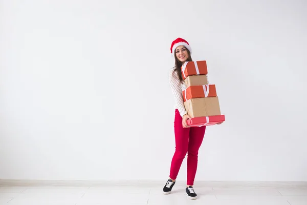 Різдво, свята та подарунки концепція - молода жінка в капелюсі Санта тримає багато подарунків на білому тлі з місцем для тексту — стокове фото