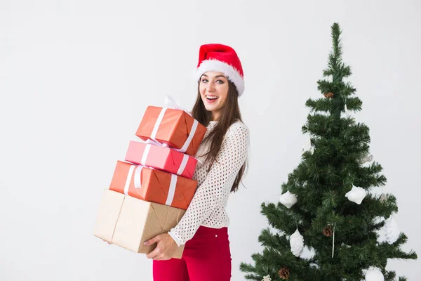 Natal, feriados e presentes conceito - mulher em santa chapéu segurando um monte de presentes no fundo branco — Fotografia de Stock