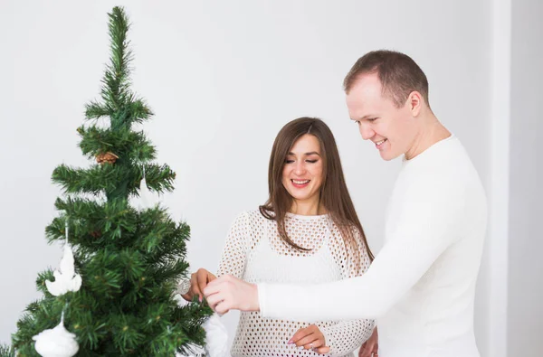 Concepto de vacaciones de invierno - Feliz pareja de amor decorando el árbol de Navidad en la habitación — Foto de Stock