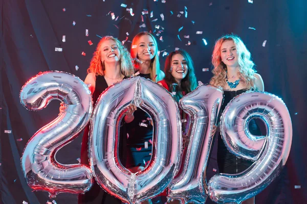 Concetto di festa di Capodanno. Gruppo di giovani donne con numeri argentati 2019 e coriandoli — Foto Stock