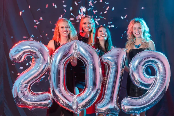 Concetto di festa di Capodanno. Gruppo di giovani donne con numeri argentati 2019 e coriandoli — Foto Stock