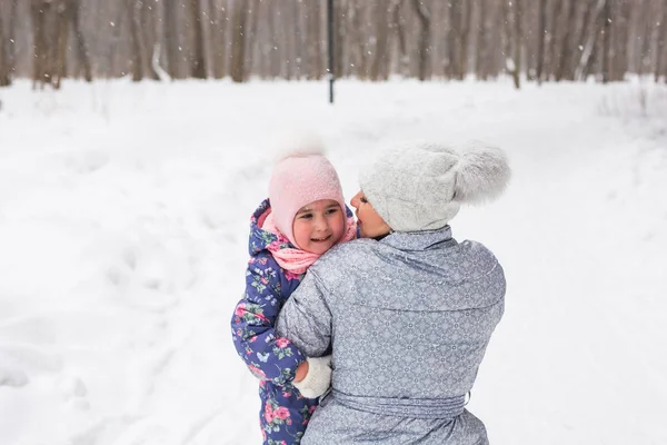Conceito de família, crianças e natureza - Jovem mãe abraçar pequena criança feliz no parque de inverno — Fotografia de Stock