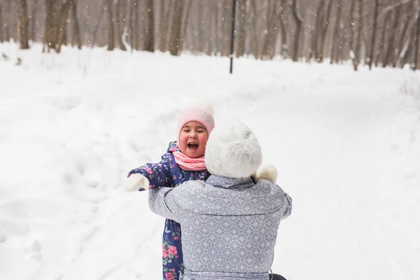 Concepto de familia, infancia y naturaleza - Joven madre abrazar a su hijita en el parque de invierno — Foto de Stock