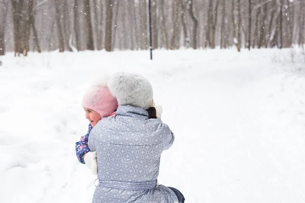 Conceito de inverno, família e infância - a mãe está andando com sua filha na floresta nevada e abraçando — Fotografia de Stock