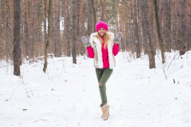Moda ve insanlar kavramı - karlı kış Park pembe sıcak ceketli duran çekici genç kadın