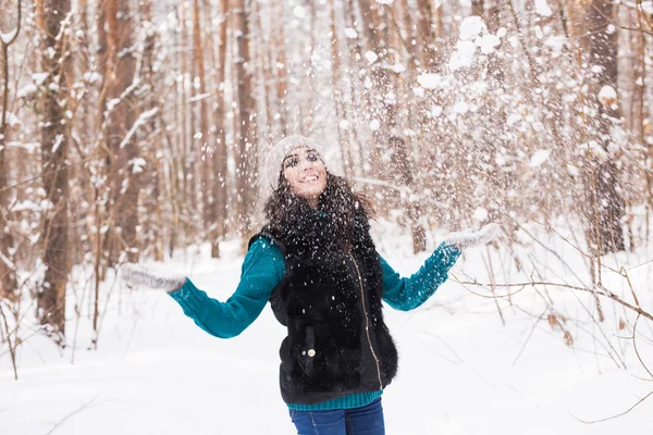 Temporada, lazer e conceito de pessoas - jovem mulher é feliz e jogando neve na natureza de inverno — Fotografia de Stock