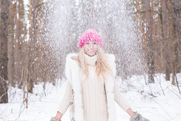 Diversión, invierno y concepto de la gente - Mujer joven atractiva vestida con abrigo lanzando nieve . — Foto de Stock