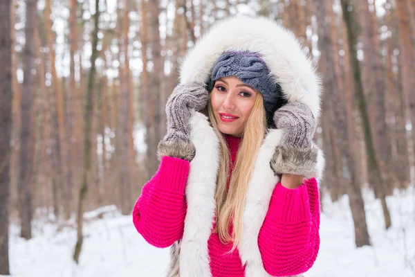 Inverno, conceito de beleza e moda - Retrato de mulher jovem loira em casaco de peles no fundo da natureza nevada Imagem De Stock