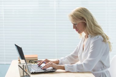Çalışma, iş, teknoloji ve insan kavramı - ofis dizüstü bilgisayar ile çalışmaya ve notlar yazma genç kadın