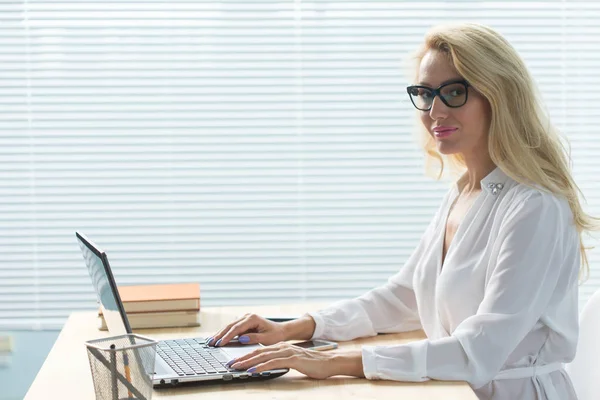 Business, technologie et concept de personnes - jeune femme blonde travaillant dans un ordinateur portable et souriant — Photo