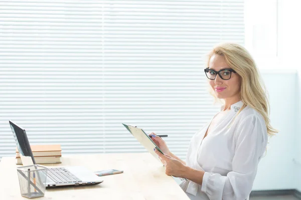 Concept de technologie, d'affaires et de personnes - Belle femme en lunettes travaillant à l'ordinateur et prenant des notes — Photo