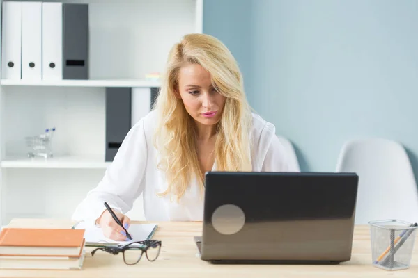 Concept technologie, travail et personnes - Belle femme blonde assise à son bureau et travaillant sur un ordinateur portable — Photo
