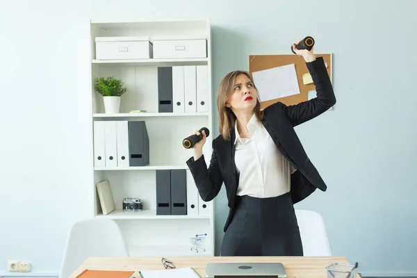 Podnikání, emoce a lidmi koncept - žena v kanceláři, v ruce drží činky — Stock fotografie