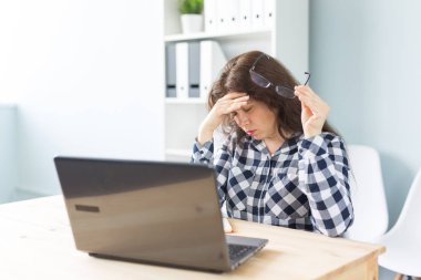 Teknoloji, iş ve insan kavramı - genç kadın laptop önünde oturan alın yakınındaki el ile şaşkın