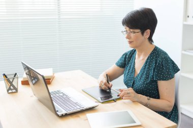 Office, grafik tasarımcı, dijital - dizüstü bilgisayar ve dijital tablet ofisinde çalışan orta yaş kadın