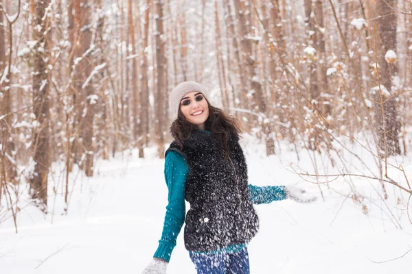 Temporada, lazer e conceito de pessoas - jovem mulher é feliz e jogando neve na natureza de inverno — Fotografia de Stock