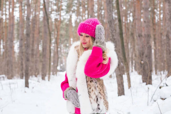 Ομορφιά, μόδα και άνθρωποι έννοια - ελκυστική ξανθιά γυναίκα στέκεται σε ροζ καπέλο και πουλόβερ χειμώνα ξύλο και χαμογελαστός — Φωτογραφία Αρχείου