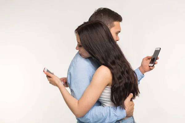 Smartphone addiction concept - Young couple using internet on mobile phone, ignoring each other. They are bored and sad — Stock Photo, Image