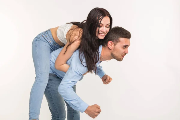 Pareja posando sobre fondo blanco - hombre sosteniendo a mujer en su espalda —  Fotos de Stock