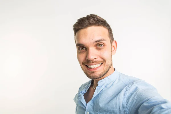 Μόδα και οι άνθρωποι έννοια - όμορφος άνδρας κάνει μια selfie φωτογραφία και χαμογελαστός σε λευκό φόντο — Φωτογραφία Αρχείου