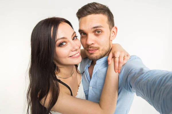 Relation et les gens concept- homme prenant selfie avec sa merveilleuse femme sur téléphone portable sur fond blanc — Photo