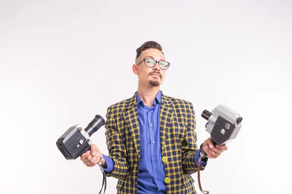 Technologies, photographing and people concept - portrait of funny young brunette man taking selfie with two cameras on white background — Stock Photo, Image