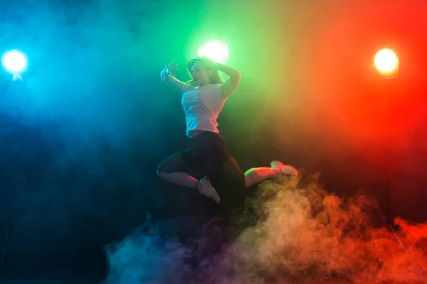 Concetto di danza, sport, jazz funk e people - giovane donna che si tuffa nell'oscurità sotto una luce colorata — Foto Stock